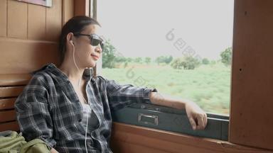 亚洲女人穿太阳镜听音乐耳机火车窗口铁路火车开始曼谷北泰国享受运输古董火车